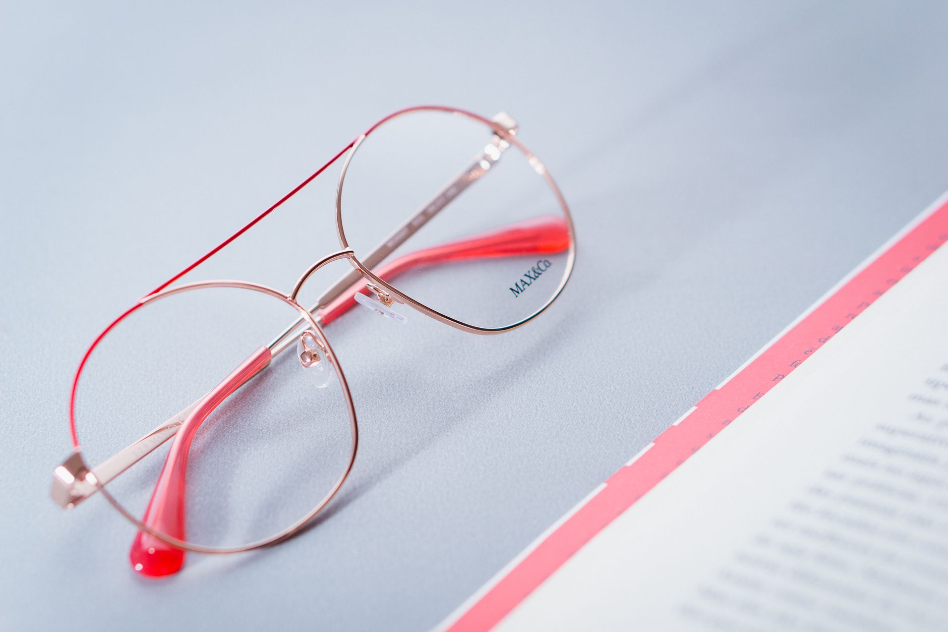 Close-up of stylish red-rimmed eyeglasses on a desk next to an open document.