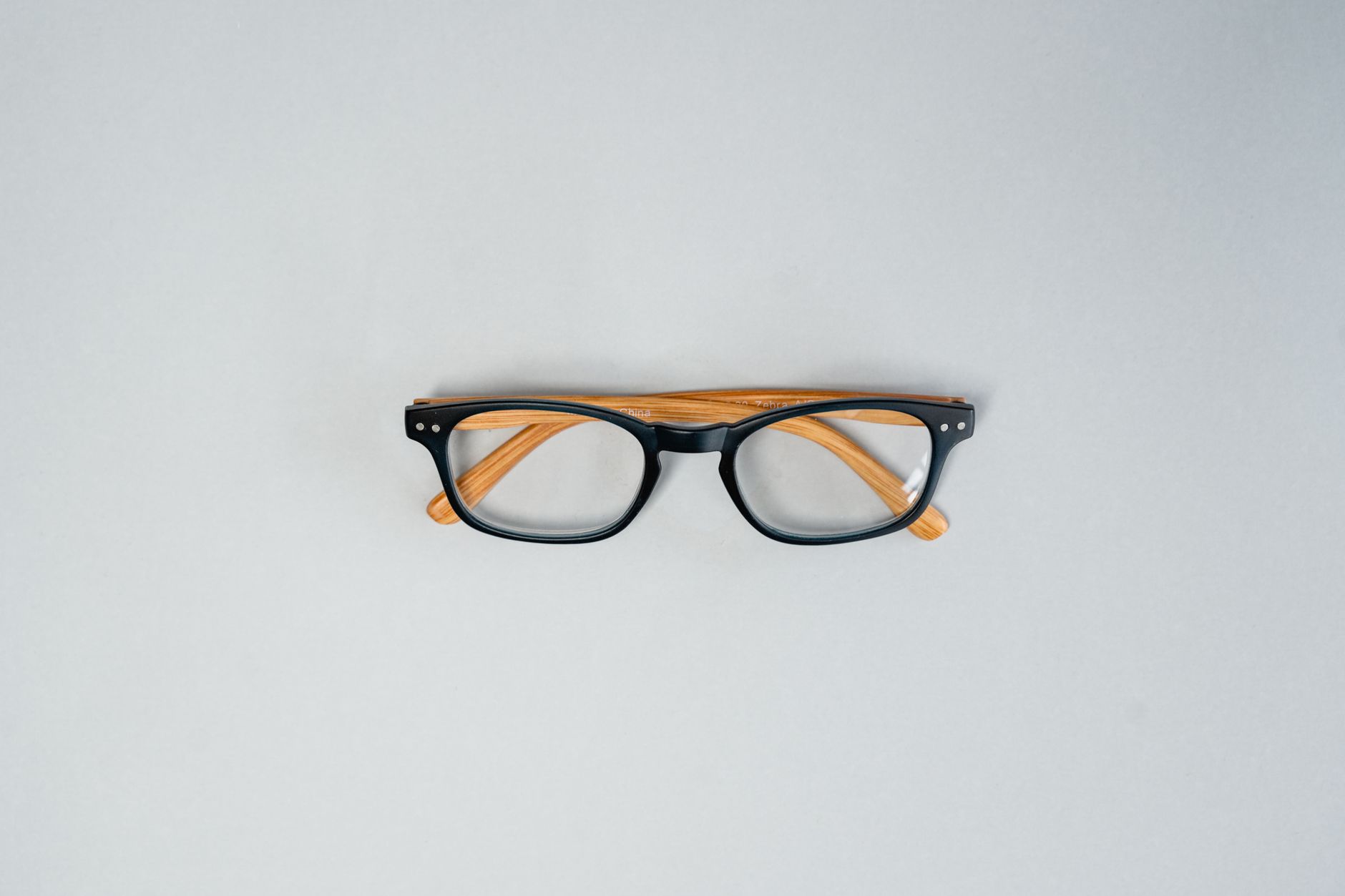 Stylish black square glasses with wooden arms on a white background, minimalist style.